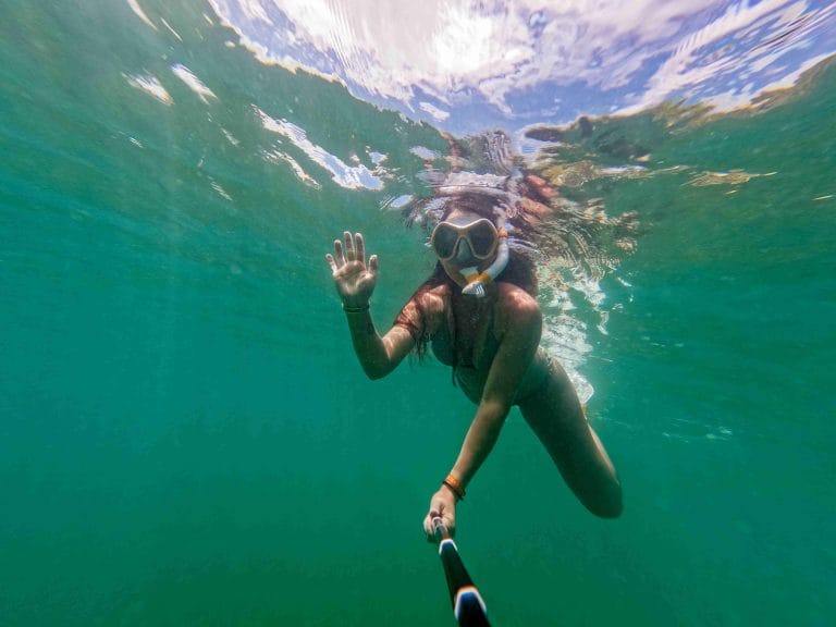Girl holding a selfie stick snorkeling in Playa Flamingo Guanacaste, Costa Rica