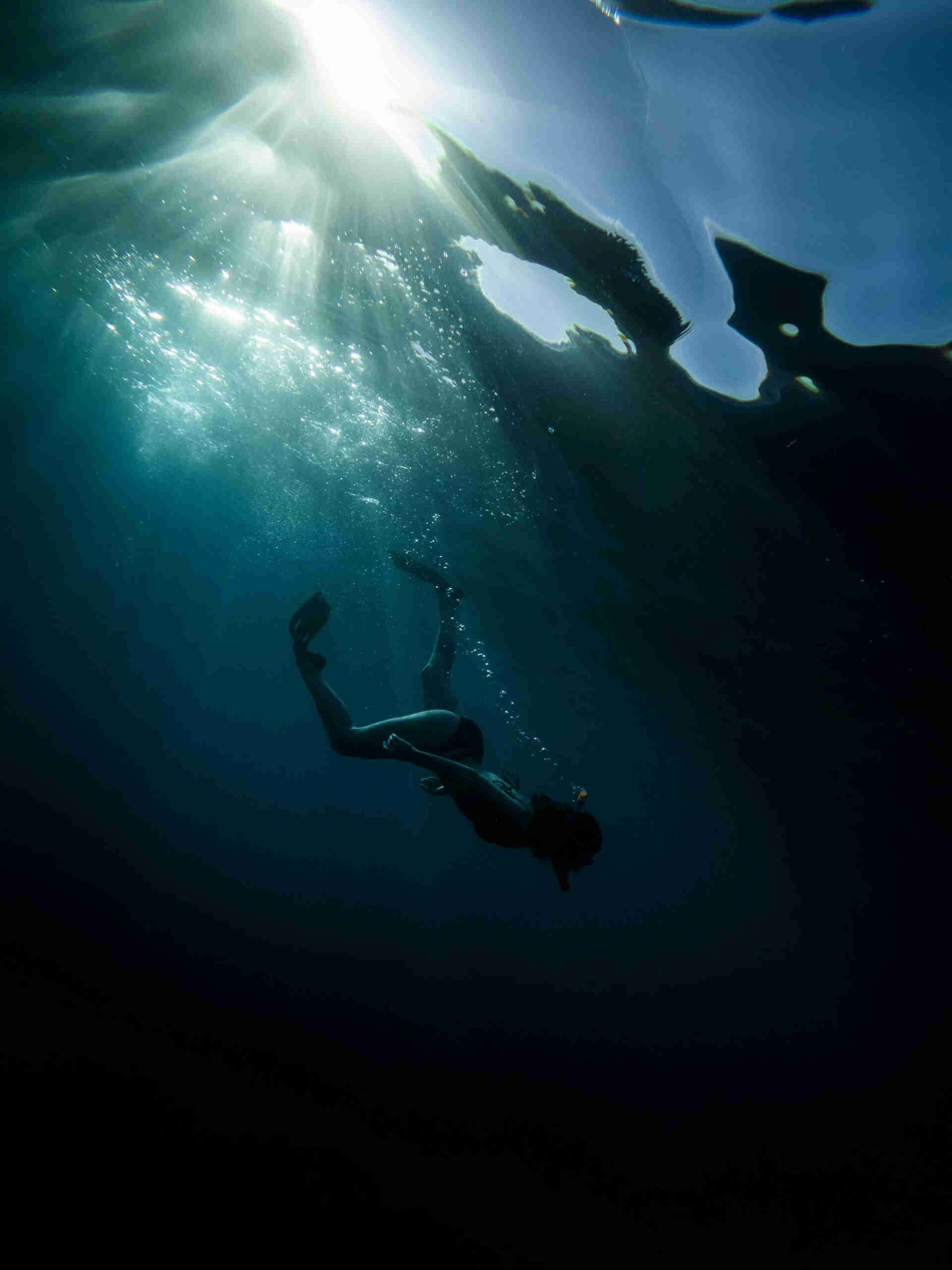 Client snorkeling in the Pacific Ocean of Costa Rica, deep blue background with light shining through