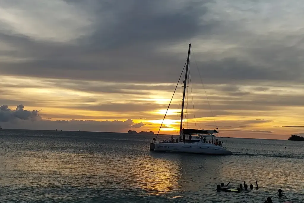 Catamaran sailing at sunset off Playa Potrero with swimmers in the water, Guanacaste, Costa Rica
