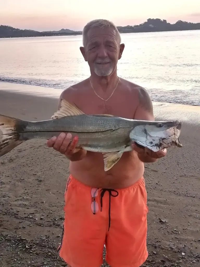 Angler holding a snook caught surf fishing at Playa Potrero, Costa Rica