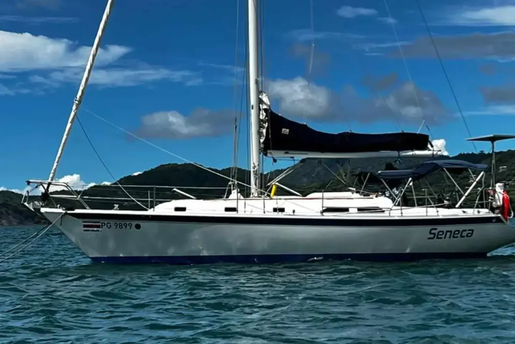 Seneca, a 38-foot Ericson sailboat, anchored in calm blue water off Playa Potrero, Costa Rica, with a green forested hillside behind