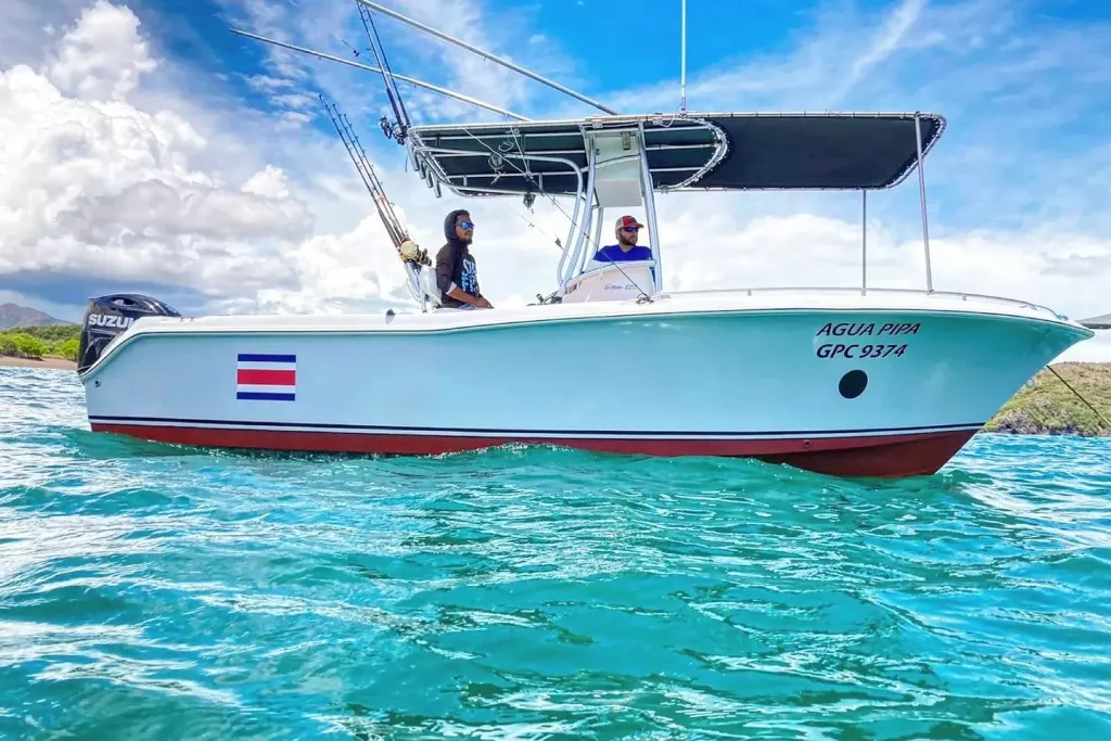 The Sea Hunt fishing charter boat with anglers aboard in the teal waters off Playa Potrero, Guanacaste, Costa Rica