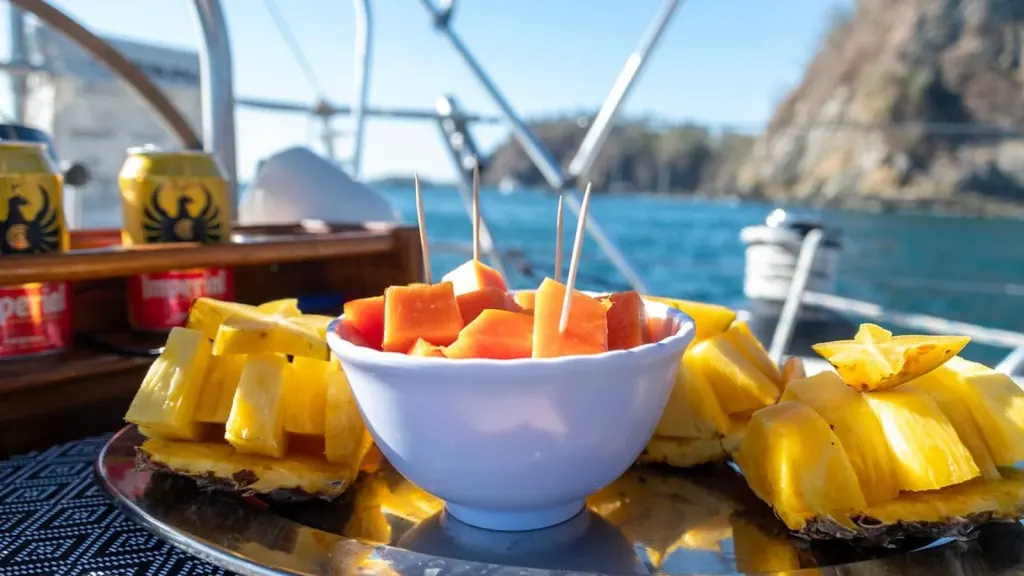 A platter of fresh pineapple, papaya, and starfruit with cold Imperial beers on board the Seneca, part of the all-inclusive private sailing charter
