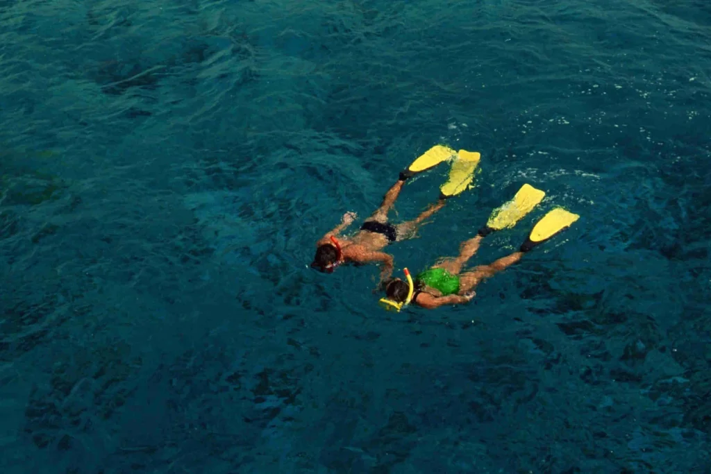 Two snorkelers with yellow fins swimming side by side in the deep blue water off Playa Potrero, Costa Rica